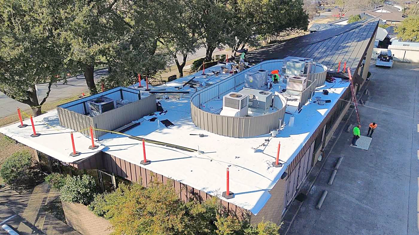 Aerial view of a commercial flat roof being replaced, with rooftop units and new insulation board down