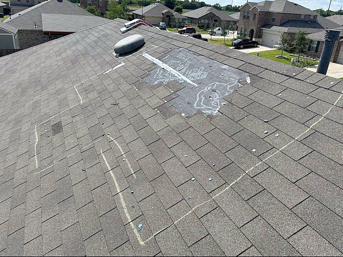 Chalk marks circling hail hits on a shingle roof during an inspection