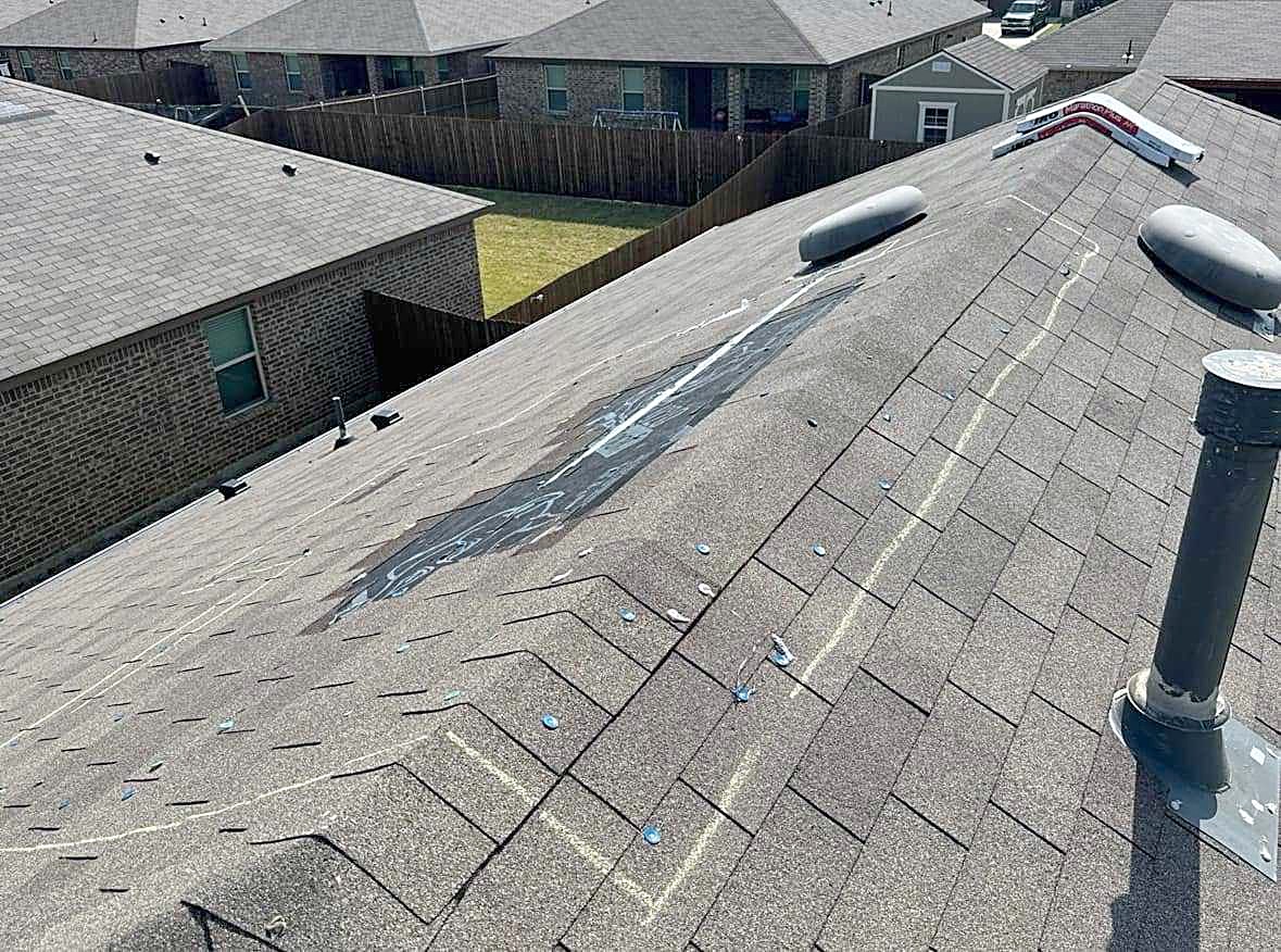 A shingle roof with storm damage marked in chalk around the vents